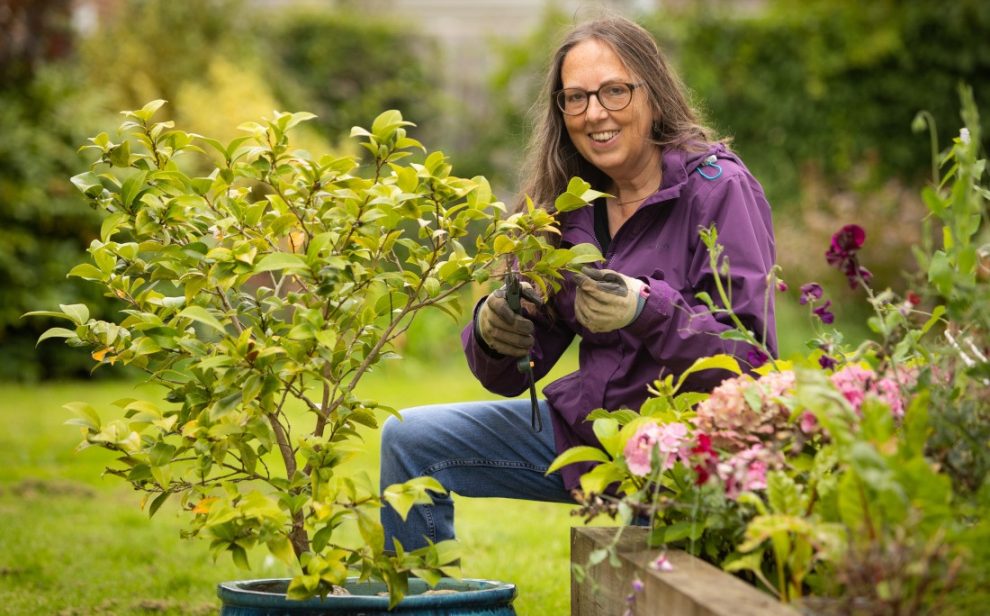 Woman on raised bed pruning a plant
