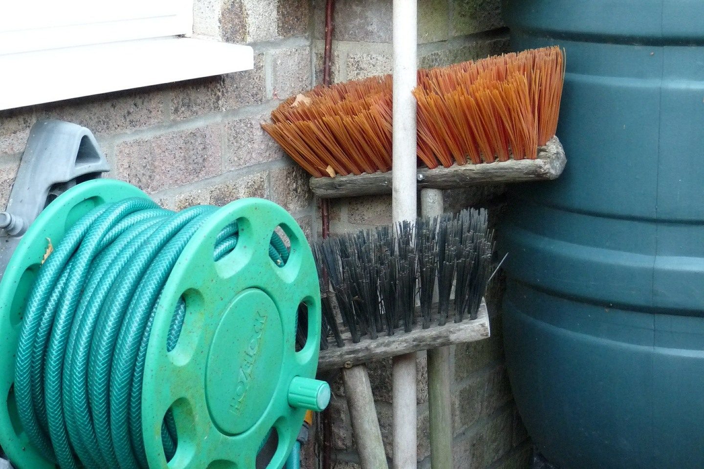 A garden hose together with water butt and brooms