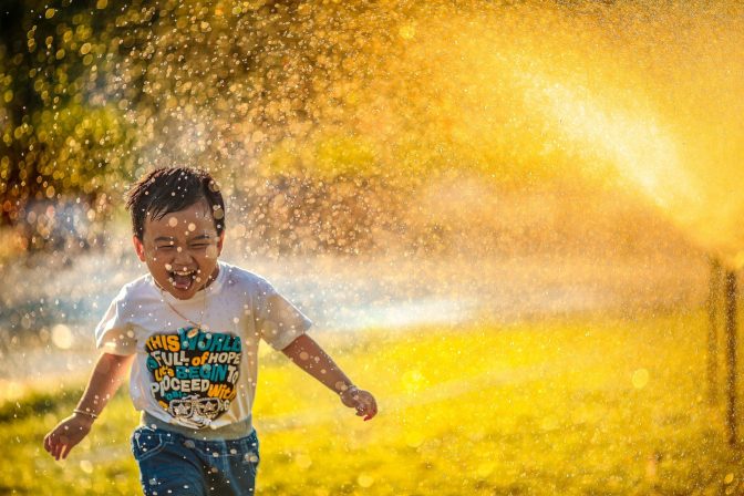 Child playing under sprinkler unsplash