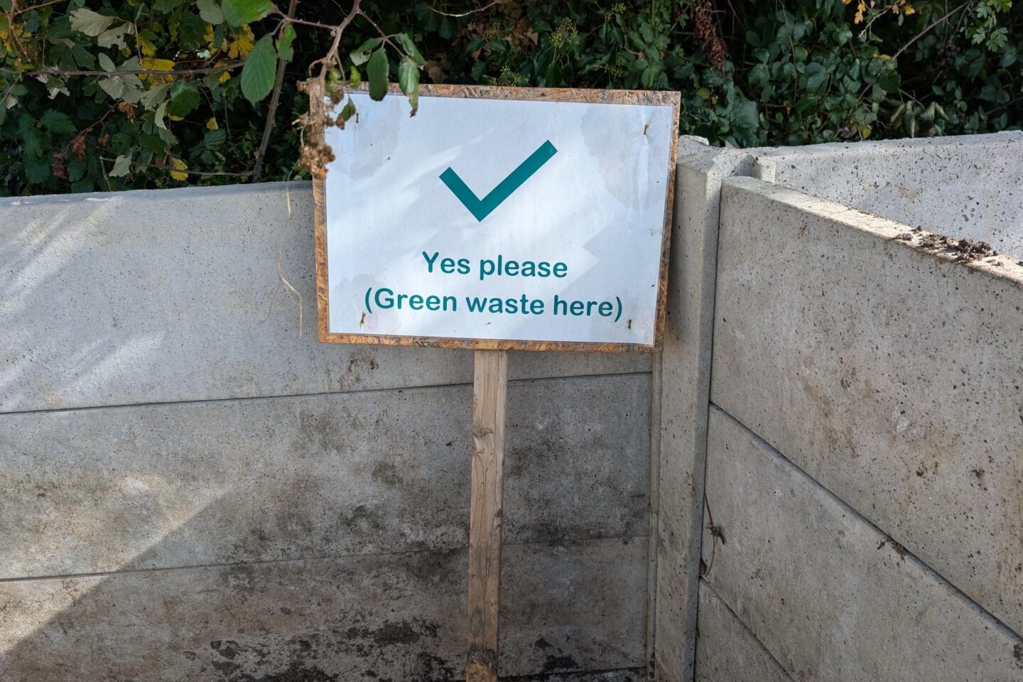 A label on a compost pile with a tick to add material