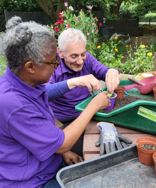 The Sanctuary Garden Volunteer with client gardener potting up seedlings web