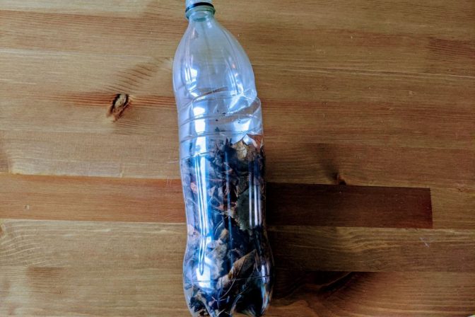 Large clear plastic bottle filled with layers of compost material